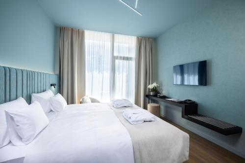 a hotel room with a bed with white sheets and a television at Viale Boutique Hotel in Villány