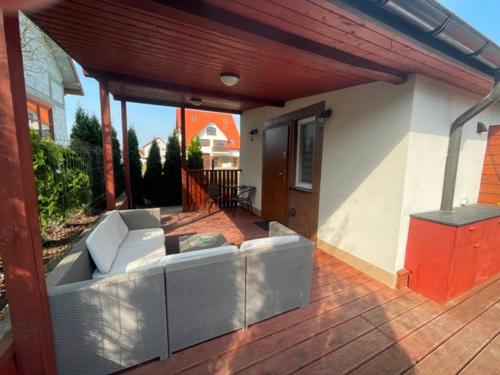 a patio with a couch on a wooden deck at Ośrodek Dalpol in Prażmowo