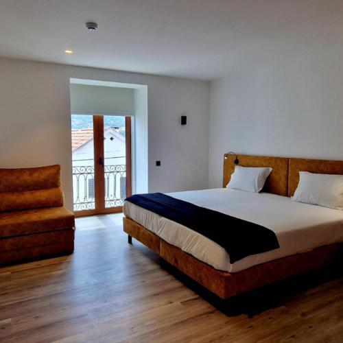a bedroom with a large bed and a chair at Foz House Sabor & Douro in Torre de Moncorvo