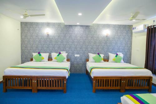 two beds in a room with blue carpet at Treebo Golden Terminal, Kochi Airport in Cochin