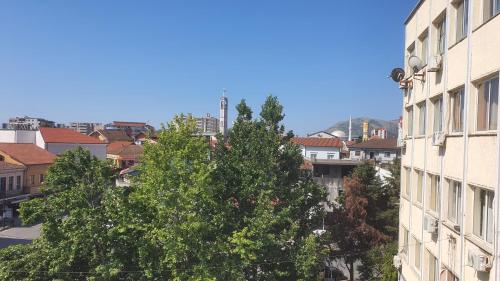a building and a tree in front of a city at Helios Hotel&Hostel in Shkodër