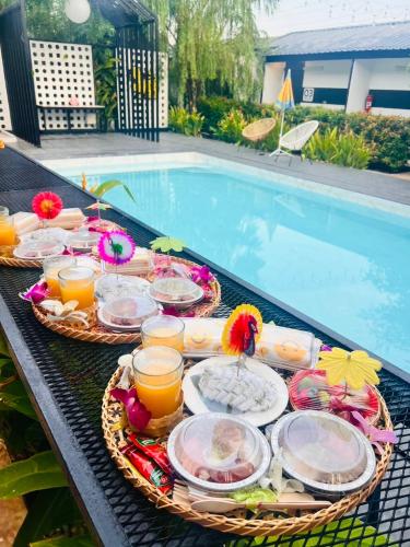 a table with plates of food next to a swimming pool at Penguin Villa Resort & Bistro in Ratchaburi