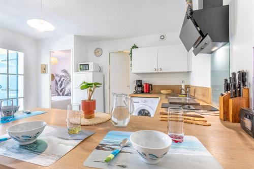 - une cuisine avec une table en bois et des bols dans l'établissement La belle petite maison d'Oléron, à Dolus-d'Oléron