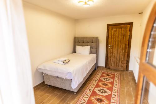 a small bedroom with a bed and a wooden door at Ayaz Stone House in Goreme