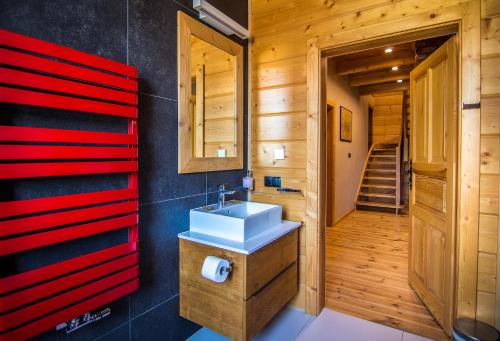a bathroom with a sink and a red wall at Etiuda Zakopane in Zakopane