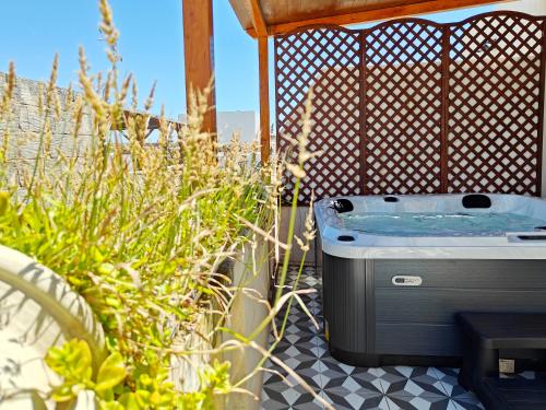 a hot tub sitting on a patio with plants at Zebbuga Deluxe Lavish Suite 3 in Żebbuġ