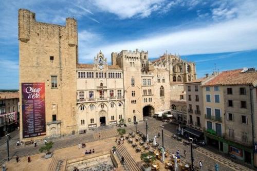 un grand bâtiment avec une tour d'horloge dans une ville dans l'établissement Le Limouzy - appartement proche des halles, à Narbonne