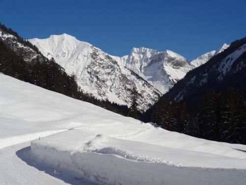 a snow covered mountain range with a road in the snow at Gästehaus Koros in Fischen