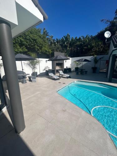 een zwembad naast een patio met parasols bij The Sanctuary Guest House in East London