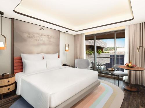 a bedroom with a large white bed and a table at Novotel Goa Panjim in Panaji