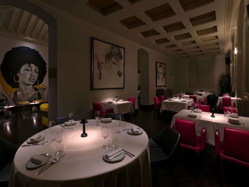 a restaurant with white tables and chairs and a painting at Fairmont Tazi Palace Tangier in Tangier