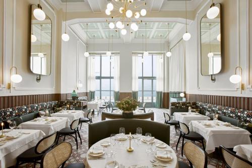 a restaurant with white tables and chairs and a chandelier at ON Residence - Small Luxury Hotels of the World in Thessaloniki