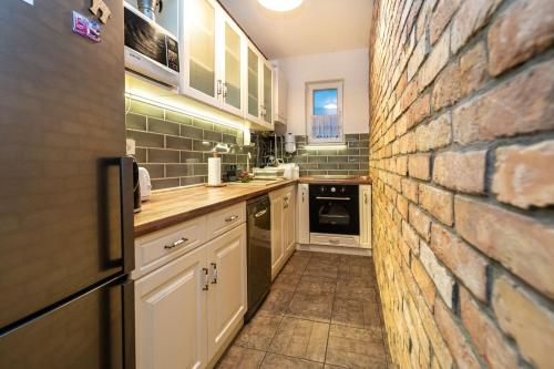 a kitchen with a brick wall and white cabinets at Vénhegyi Levendula Vendégház Mór in Mór