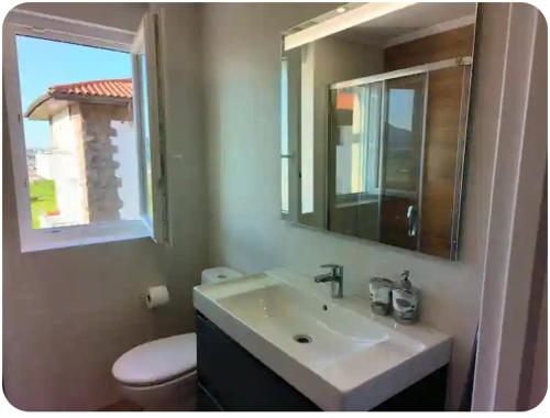 a bathroom with a sink and a mirror and a toilet at Apartamento El Muro in Laredo