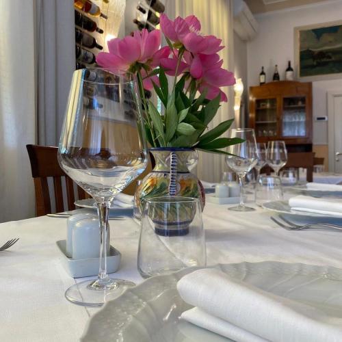 a table with glasses and a vase with pink flowers at Hotel Chenno in Subbiano