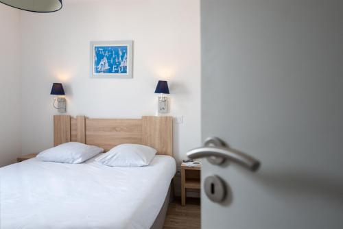 a bedroom with a white bed and a sink at Résidence Prestige Odalys Le Domaine des Pins in Noirmoutier-en-l'lle