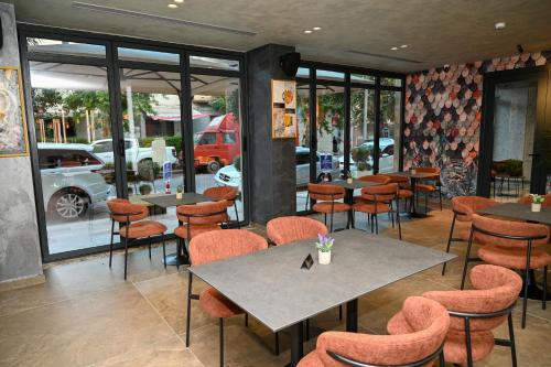 a restaurant with tables and chairs and windows at Ermes Luxury Hotel in Durrës