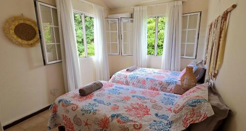 a bedroom with a bed and two windows at LAKAZ DEL SOL - Modern and elegant apartments with luxurious garden, pool and barbecue area - Tourism Permit Certified in Tamarin