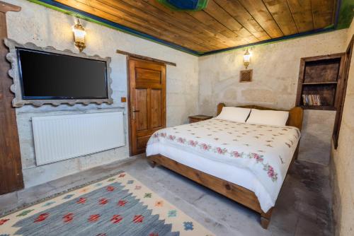 a bedroom with a bed and a flat screen tv at Chardonnay Suites Hotel in Avanos