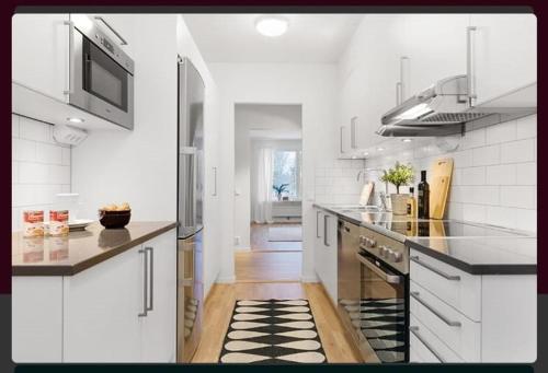 a kitchen with white appliances and a black and white rug at Comfort Us in Uppsala