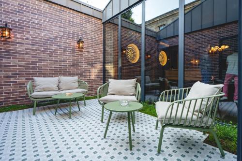 a patio with two chairs and tables and a brick building at The Originals Boutique, Hôtel Le Londres, Saumur in Saumur