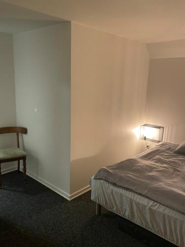 a bedroom with a bed and a chair and a lamp at Villa - private parking in Holsted