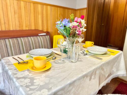 a table with a white table cloth with a vase of flowers at Уютный уголок рядом с ЦУМом и ГУМом 1 in Bishkek
