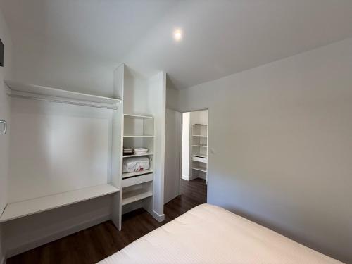 a bedroom with white walls and a white bed at Montelimar Location in Montélimar