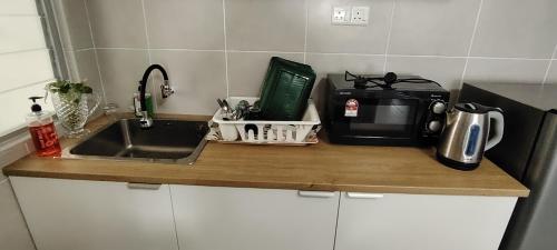 a kitchen counter with a sink and a microwave at J&K Guesthouse at Harmoni Apartment, Eco Majestic in Beranang