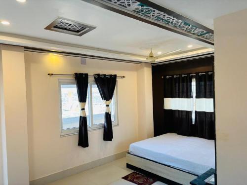 a bedroom with a bed and a window with black curtains at Hotel B N PALACE in kolkata