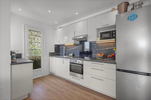 une cuisine avec des armoires blanches et des appareils en acier inoxydable dans l'établissement Cannes, Sea View, Beach Access, 3-Bedroom Apartment, 100 m2, 3 Bathrooms, Sleeps 6, 100 meters from Beach, à Cannes