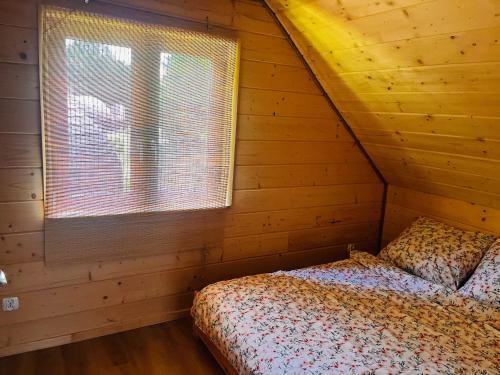 a bedroom with a bed and a window in a log cabin at GRASÓWKA in Werlas