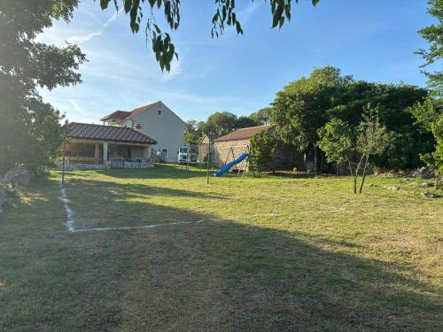 a yard with a house and a playground at Villa Magic with heated pool in Trbounje