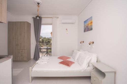 a white bedroom with a bed and a window at AnKo & AnKo 1 in Nydri
