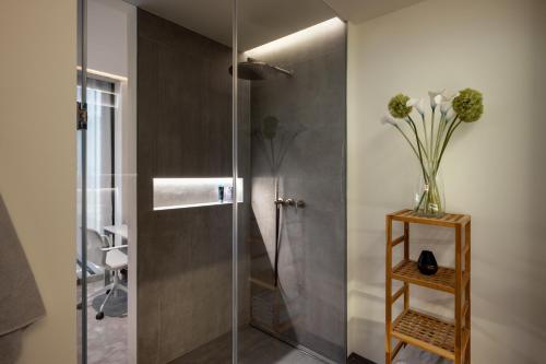 a bathroom with a shower with a vase of flowers on a table at Castle View Penthouse in Ljubljana