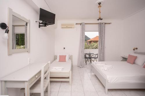 a white living room with two beds and a tv at AnKo & AnKo 1 in Nydri