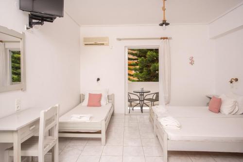 a white room with two beds and a table at AnKo & AnKo 1 in Nydri