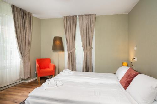 a hotel room with two beds and a red chair at BetweenLakes Apartment 1st floor in Interlaken
