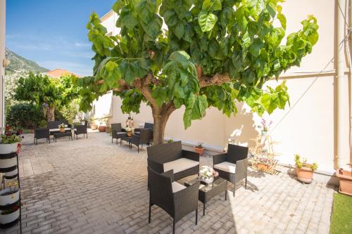 a patio with tables and chairs and a tree at AnKo & AnKo 1 in Nydri