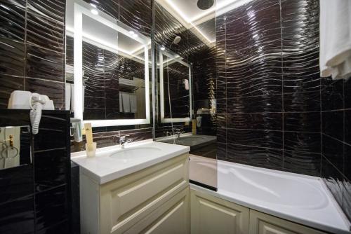 a black tiled bathroom with a sink and a shower at Kazakhstan Express in Almaty