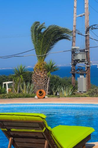 a pool with a green lounge chair and the ocean at Tethys Apartments Karfas in Chios