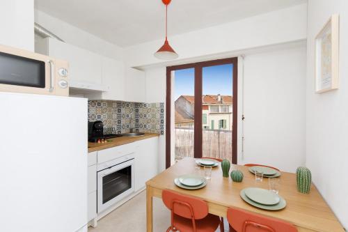 une cuisine avec une table en bois et des chaises rouges dans une pièce dans l'établissement Nice Flat with terrace & parking near city center, à Cannes