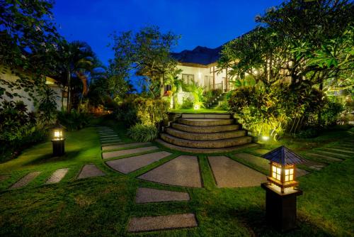 a garden at night with lights on the grass at Villa L'Orange Bali in Keramas