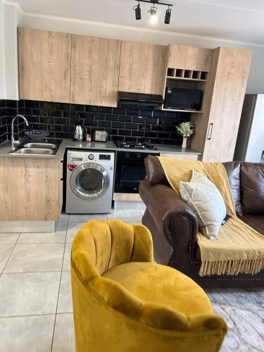 a living room with a couch and a dishwasher at Heart of Soweto Cozy Apartment in Soweto