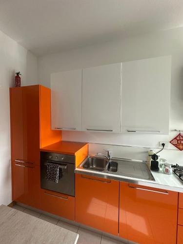 a kitchen with orange and white cabinets and a sink at Cà Vascello- Terrazza panoramica in centro in Asti