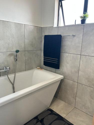 a bathroom with a bath tub and a blue towel at Heart of Soweto Cozy Apartment in Soweto