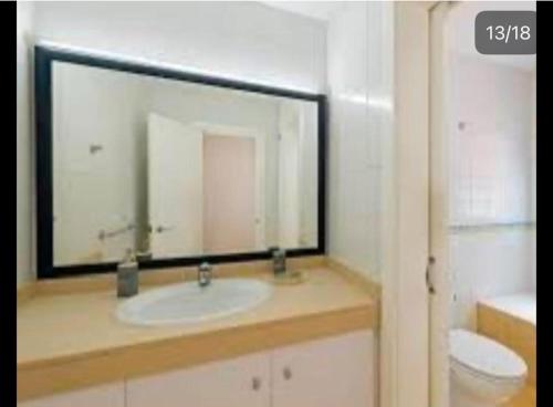 a bathroom with a sink and a mirror and a toilet at Central Rooms Cascais, Estoril in Parede