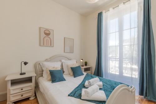 a bedroom with a bed with blue curtains and a window at Le Monnaie - Appartement lumineux face au Château de Pau in Pau
