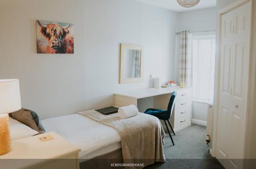 a bedroom with a bed and a desk with a laptop at Crossroads House in Carlisle