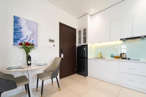 a kitchen with a table and chairs and a refrigerator at Novus Sol Hotel & Apartment Sunset Town Phu Quoc in Phu Quoc
